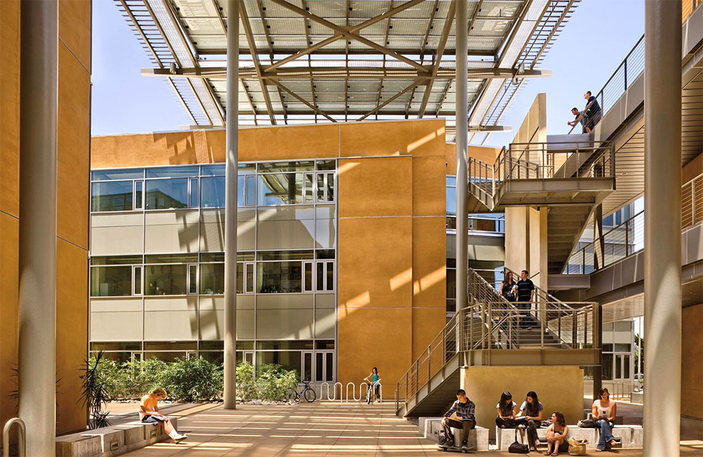 Image 5. Building courtyard featuring a metal canopy structure above and a metal staircase on the right. A 3 story building can be seen beyond the stairs.