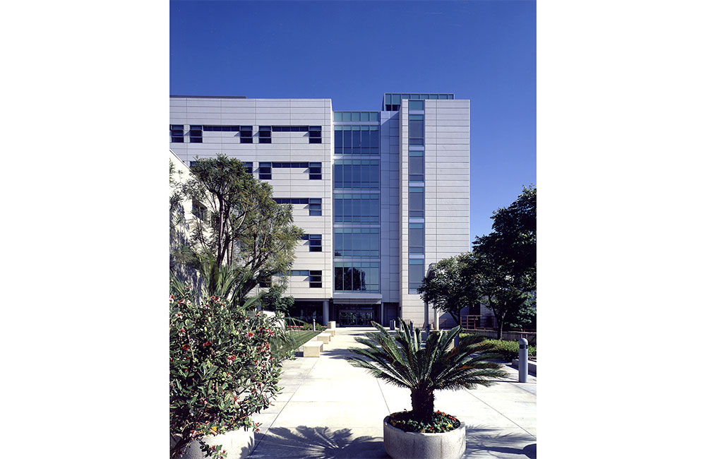 Image 3. Back corner view of 6-story modern hospital with white metal cladding.