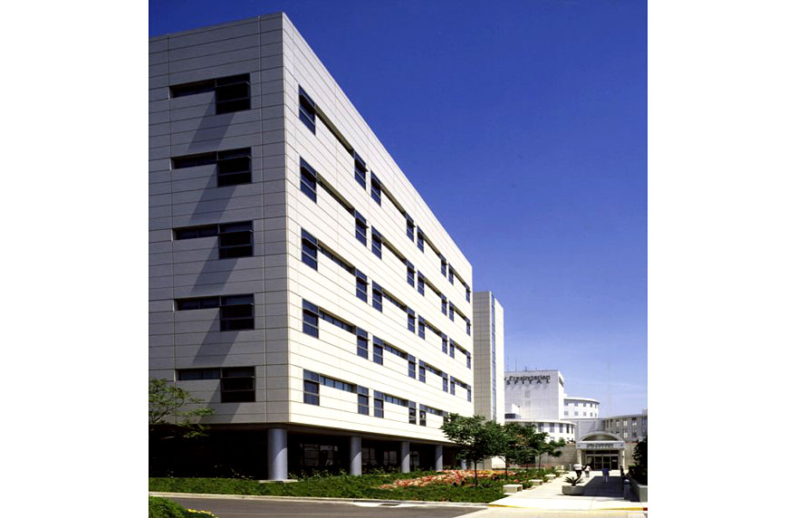 Image 4. Corner view of 6-story modern hospital with white metal cladding.