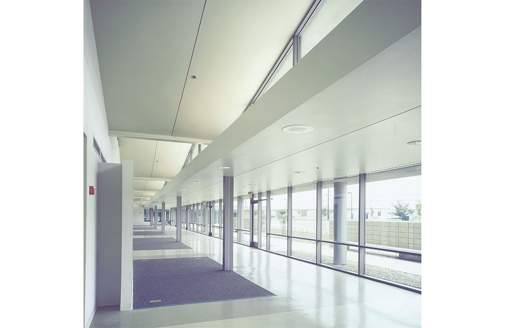 Image 5. Interior hallway showing the underside of the folded plate roof above and full height storefront system along the right.