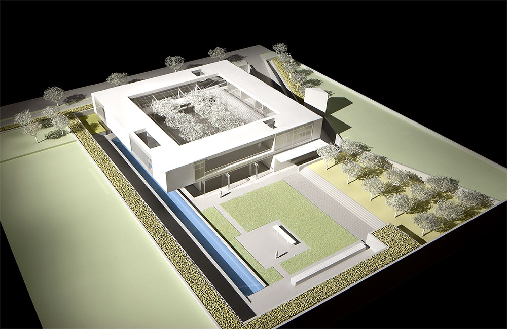 Image 6. Corner view of model showing a 2-story modern square shaped residence with a backyard lawn area and linear lap pool.
