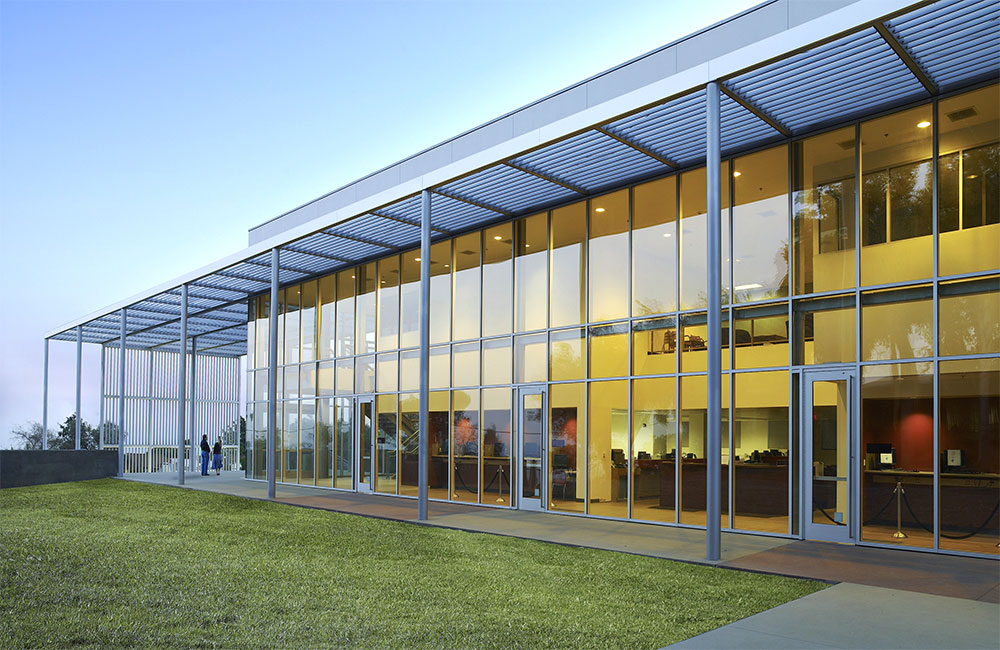 Image 3. Side exterior view of building showing glass curtain wall facade and a horizontal slatted canopy above.