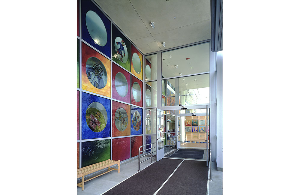 Image 3. Entry vestibule featuring multi-colored glass artwork on the left wall and giant alphabet blocks on the far right wall.